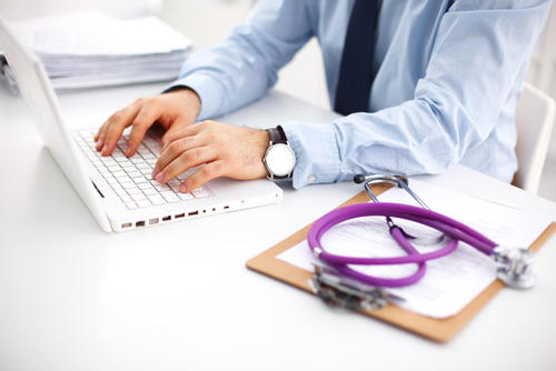 A stethoscope placed on billing paper and a billing expert is typing on laptop to give billing services to the clients